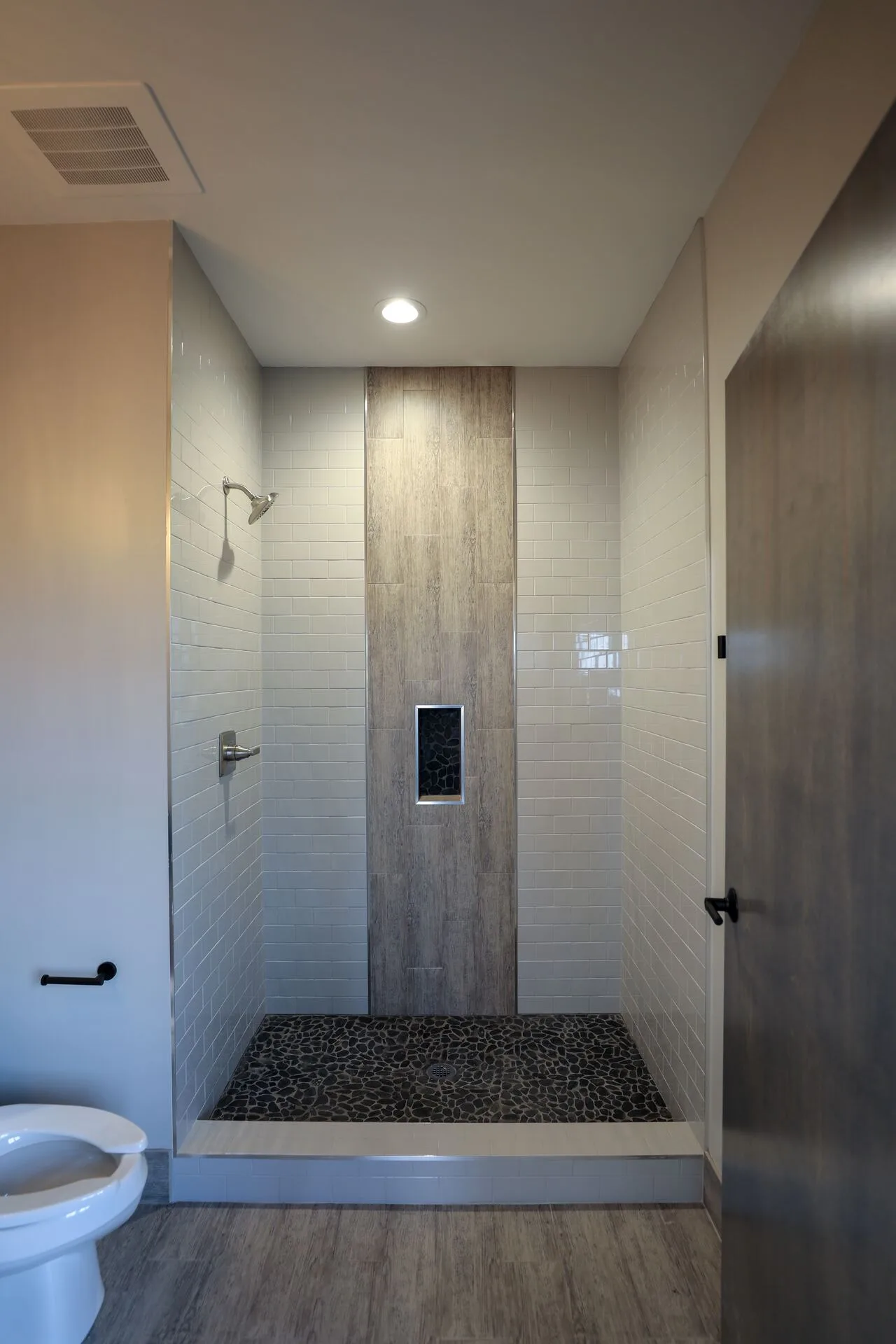 Shower stall with pebble floor and wood-look tile accent
