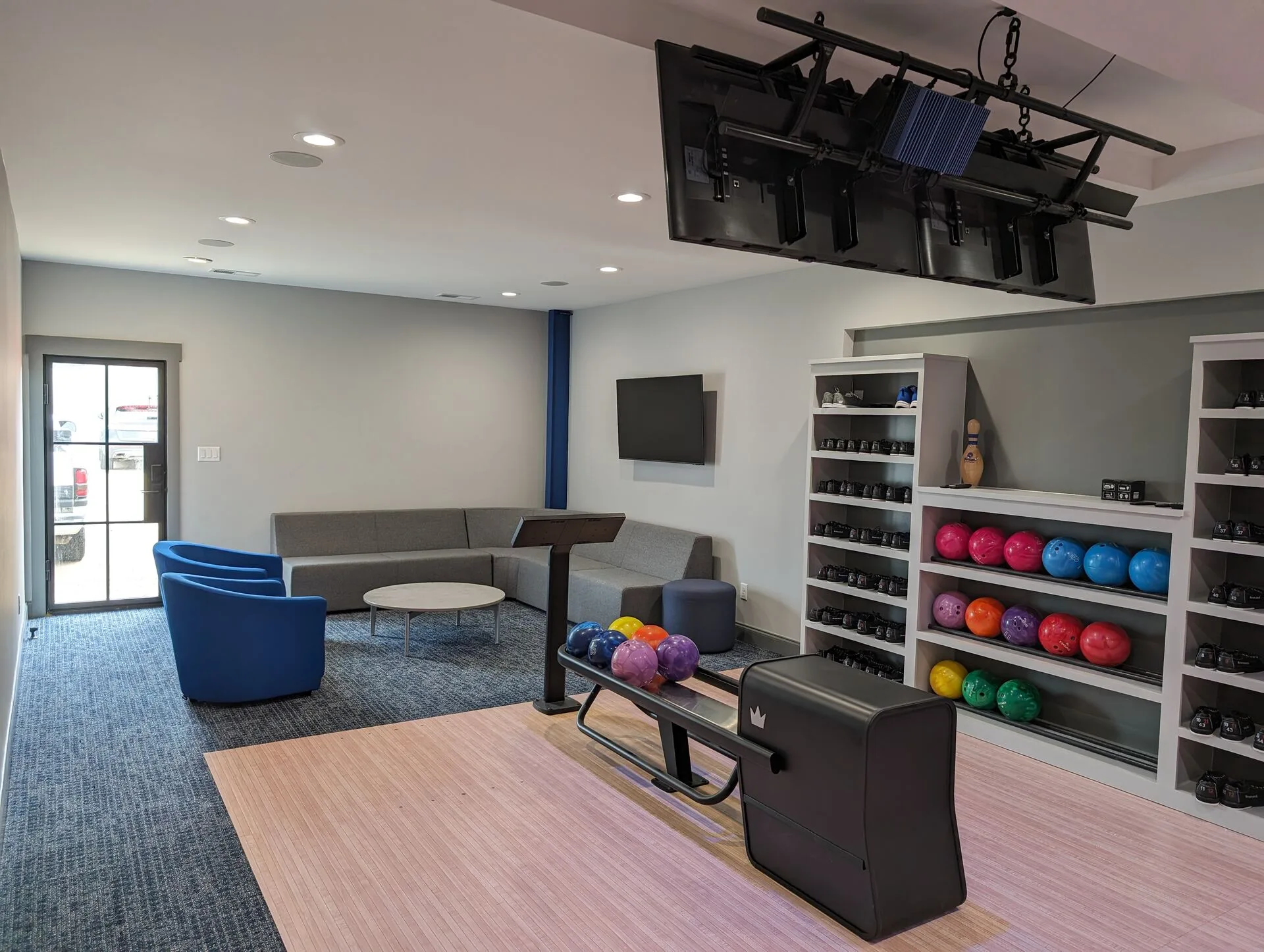 Private home gym lounge with weight rack, sofa seating, and ceiling-mounted equipment storage