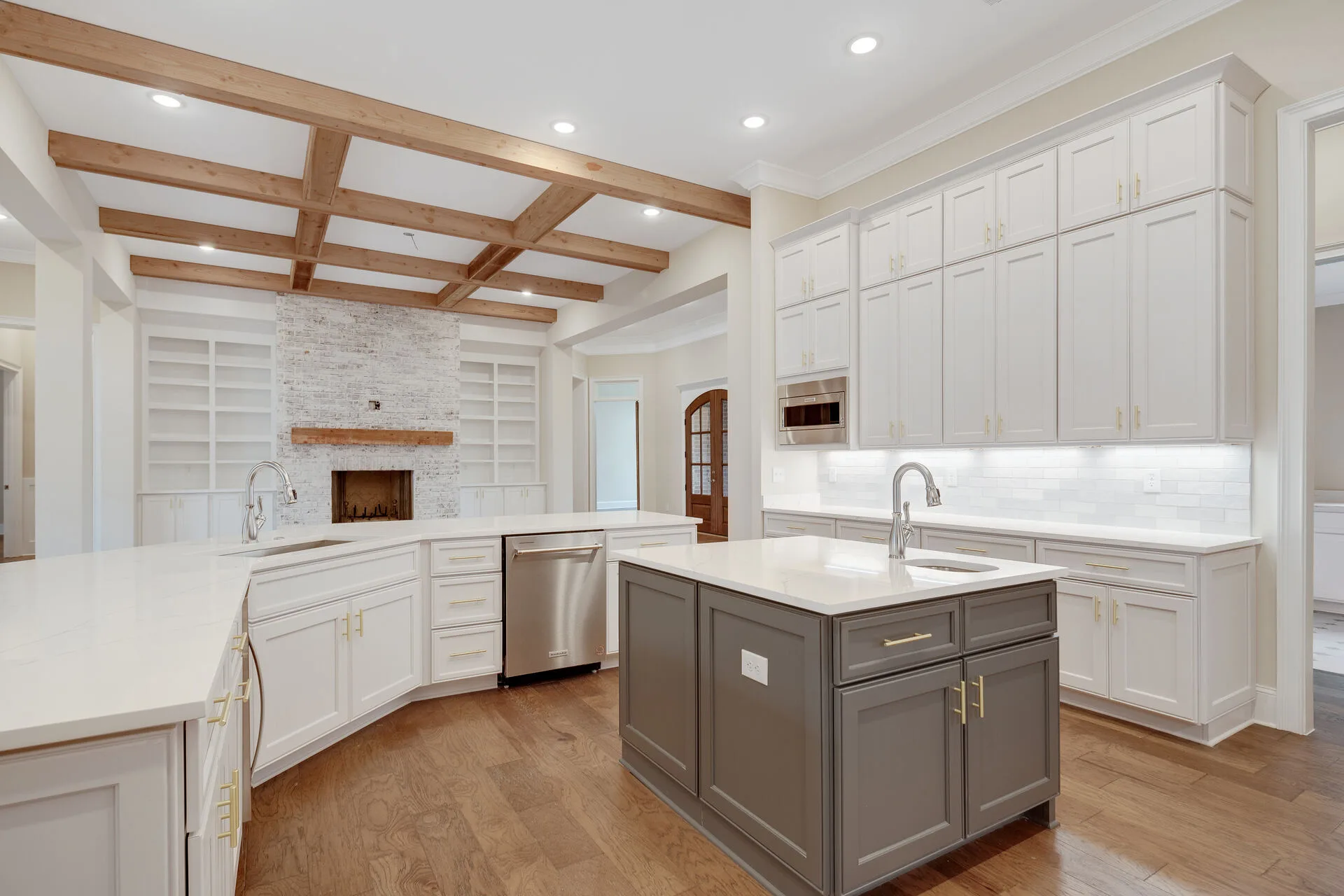 Custom gourmet kitchen with marble fireplace and coffered beam ceiling